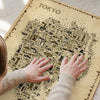 Close-up of hands touching a Tokyo Antique illustrated map poster, showing detailed landmarks and icons in a vintage sepia design.